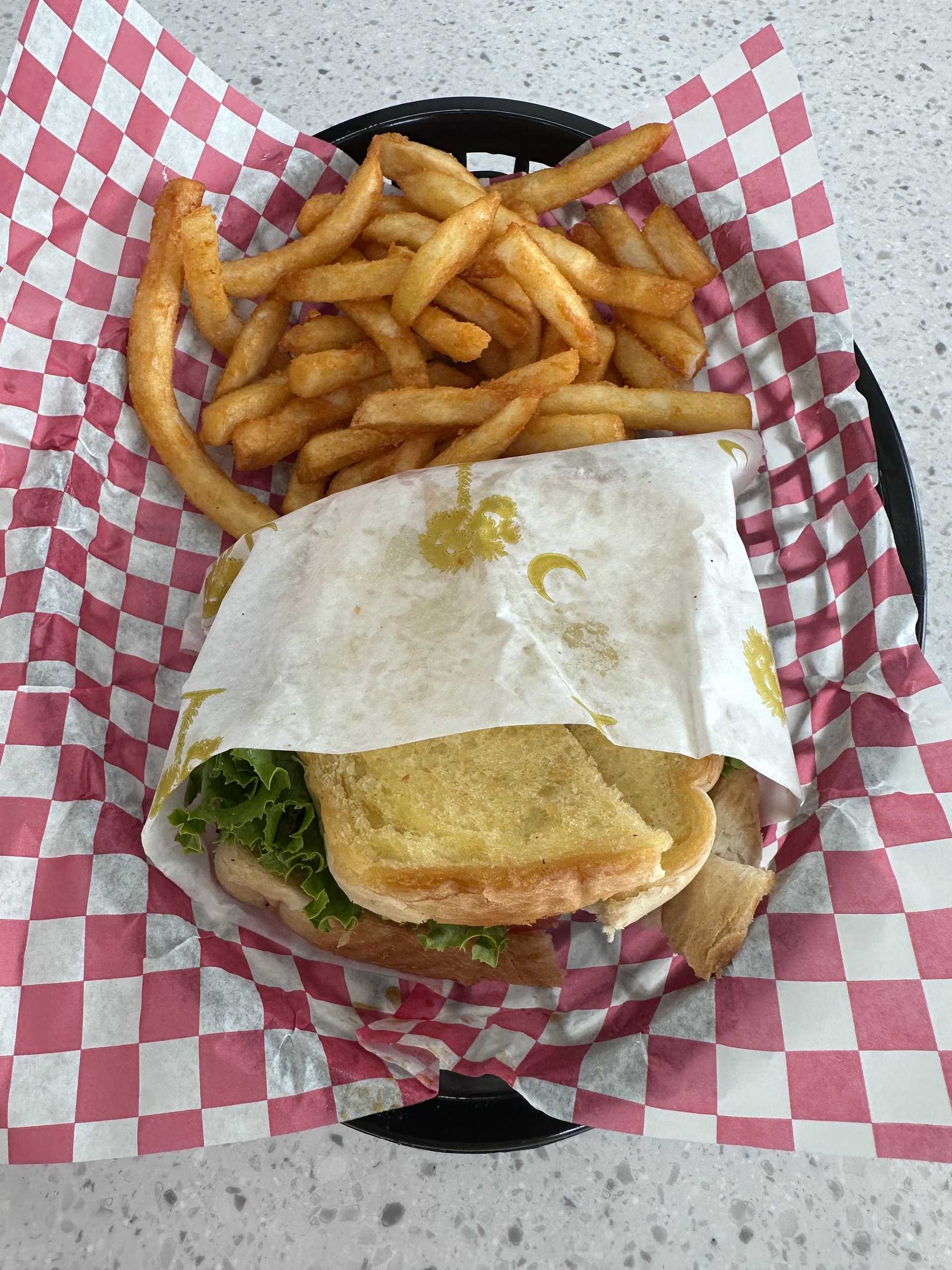 Grilled sandwich and crispy fries on red checkered paper in a basket.